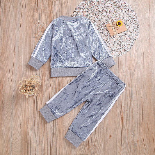 Pink velvet kids tracksuit with white stripes, cozy lounge wear set on wooden floor