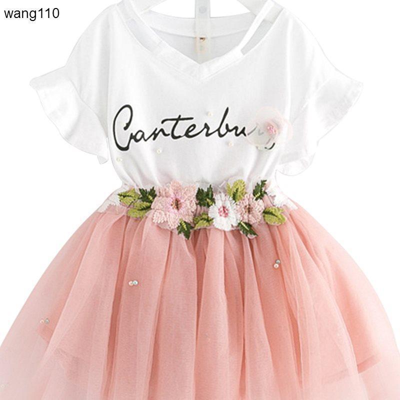 White V-neck dress with 'Canterbury' script, pink tulle skirt, floral embroidery, and pearl accents