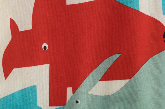 Boy wearing a Boys Short Sleeve T-Shirt by Ancient Energy with a colorful dinosaur cartoon design on the front.