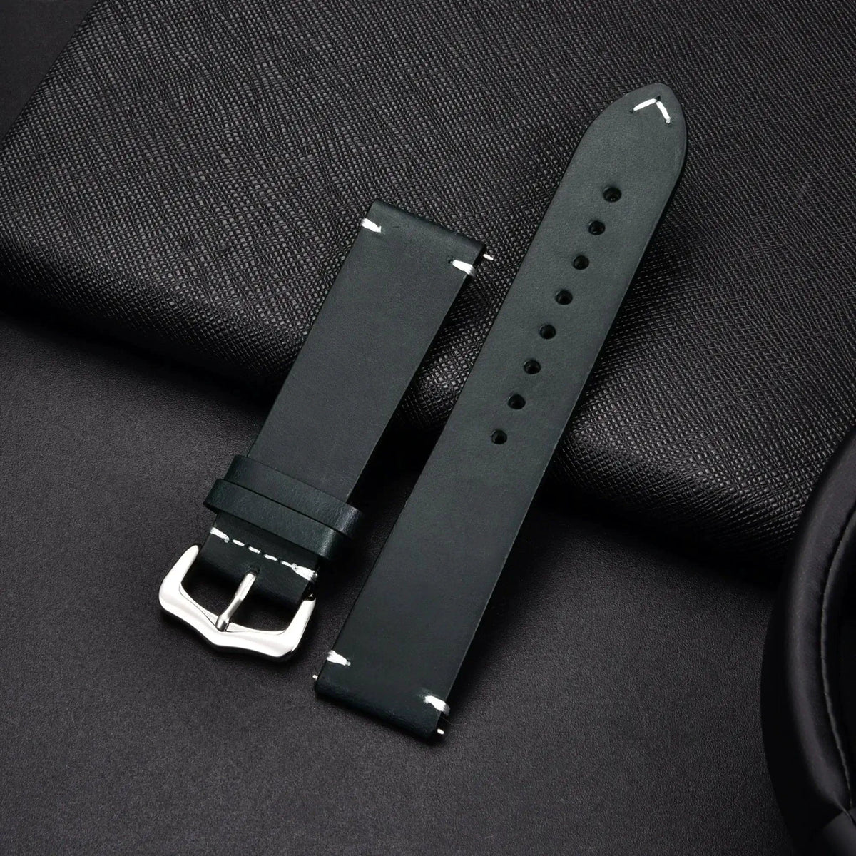 Elegant leather watch band by MANDOTOS, showing a close-up of the sleek, brown strap with stitching detail and polished metal buckle.