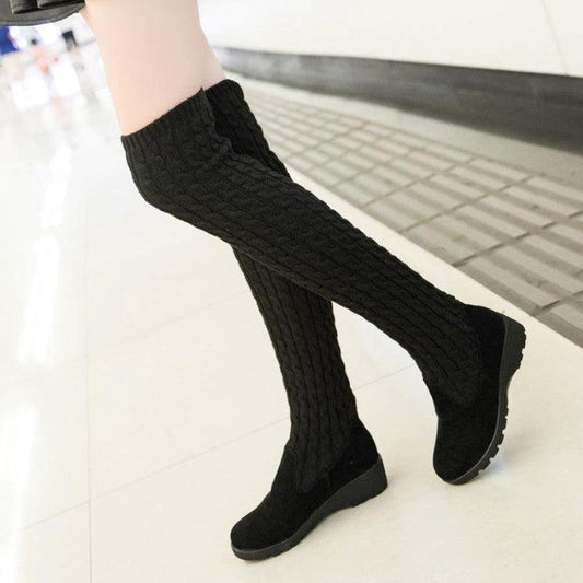 Mandotos high flat over-the-knee stretch Martin boots displayed on a model, showcasing sleek black leather and pointed toe design.