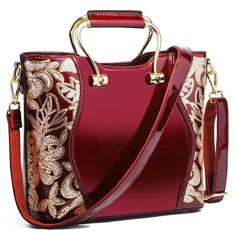 Mandotos elegant floral leather tote bag in burgundy with embroidered details and a matching crossbody strap.