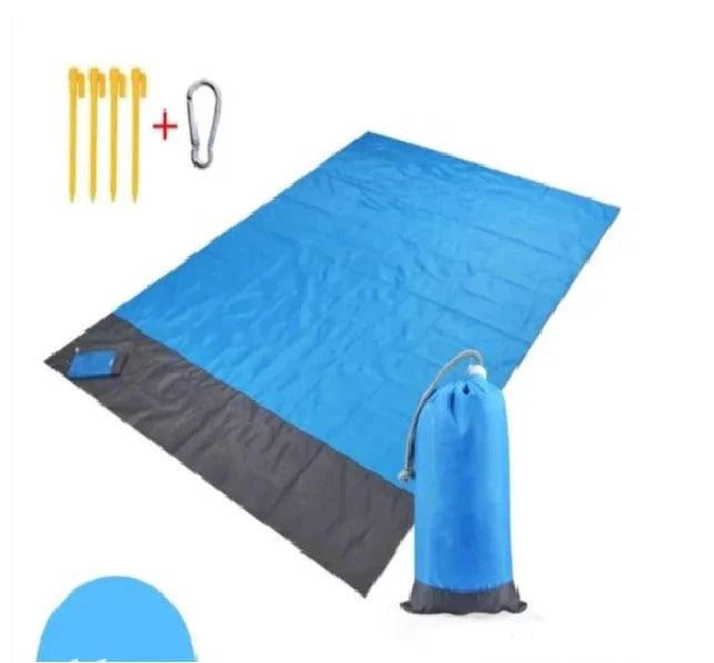 Mandotos sandproof portable beach mat laid out on sandy beach with blue sky background for outdoor relaxation.