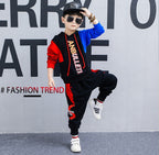 Boy in stylish red and black hoodie set with 'ANBULLET' print, sunglasses, and cap, posing for fashion trend look