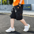 Black cargo shorts with emoji patch, worn with orange tee and white sneakers for kids' streetwear style