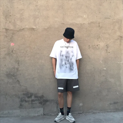 Person wearing a Mandotos International Urban Graffiti Print Tee, bucket hat, and grey shorts.
