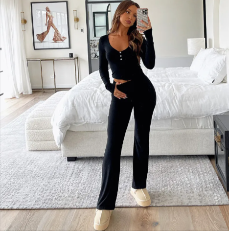 Woman wearing a black Mandotos International chic milk silk two-piece outfit with cream sneakers.