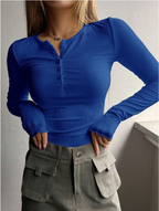 Woman wearing a Mandotos International blue ribbed half-button tee and grey trousers.