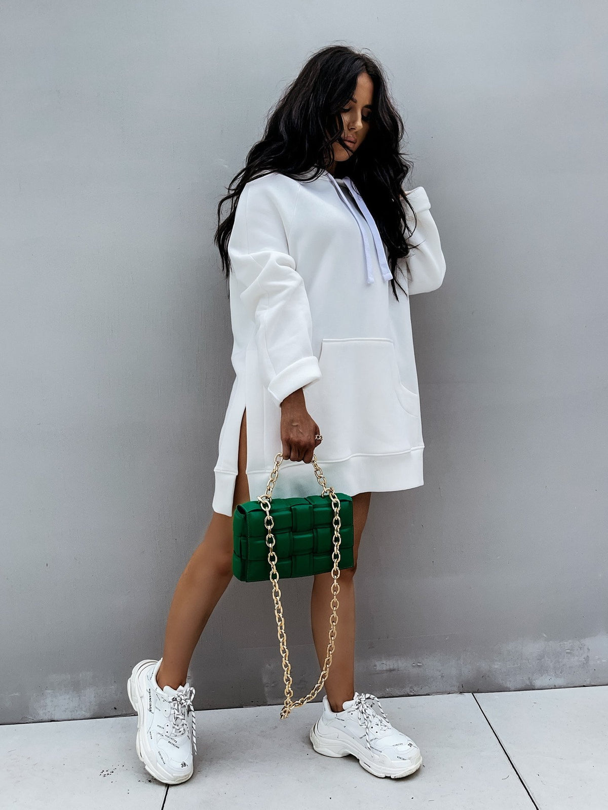 Woman wearing a Mandotos International white hooded pullover sweater and white sneakers.