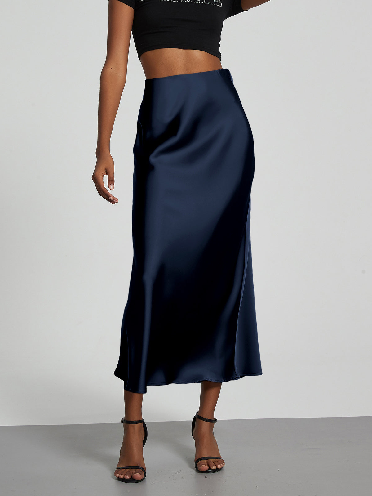 Elegant navy blue satin midi skirt with a slim, flowy silhouette worn with black sandals.
