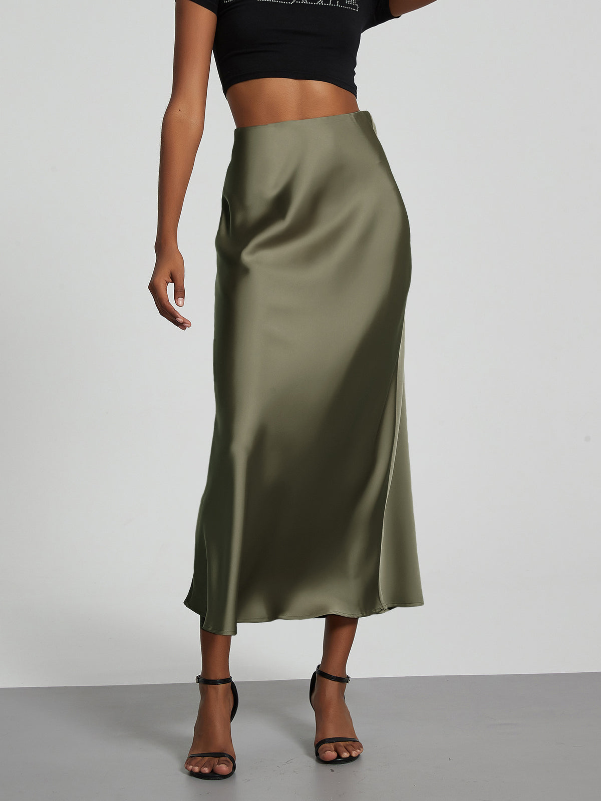 Elegant olive green satin midi skirt with a slim flowy fit worn by a model.