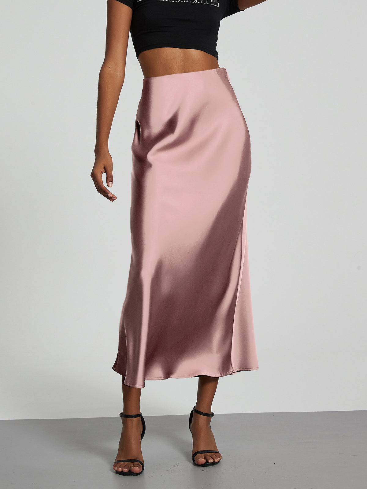 Elegant pink satin midi skirt with a slimming flowy fit worn by a model.