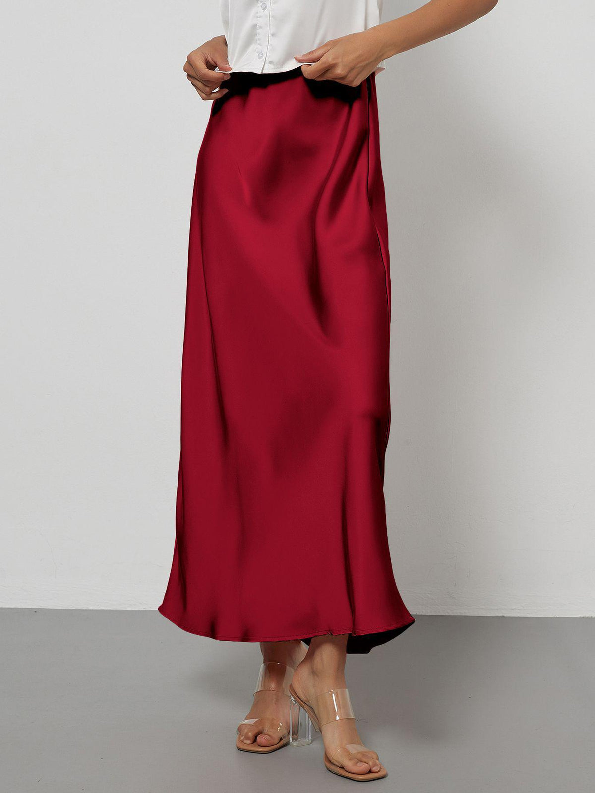 Elegant red satin midi skirt with a slim, flowy silhouette worn by a model.