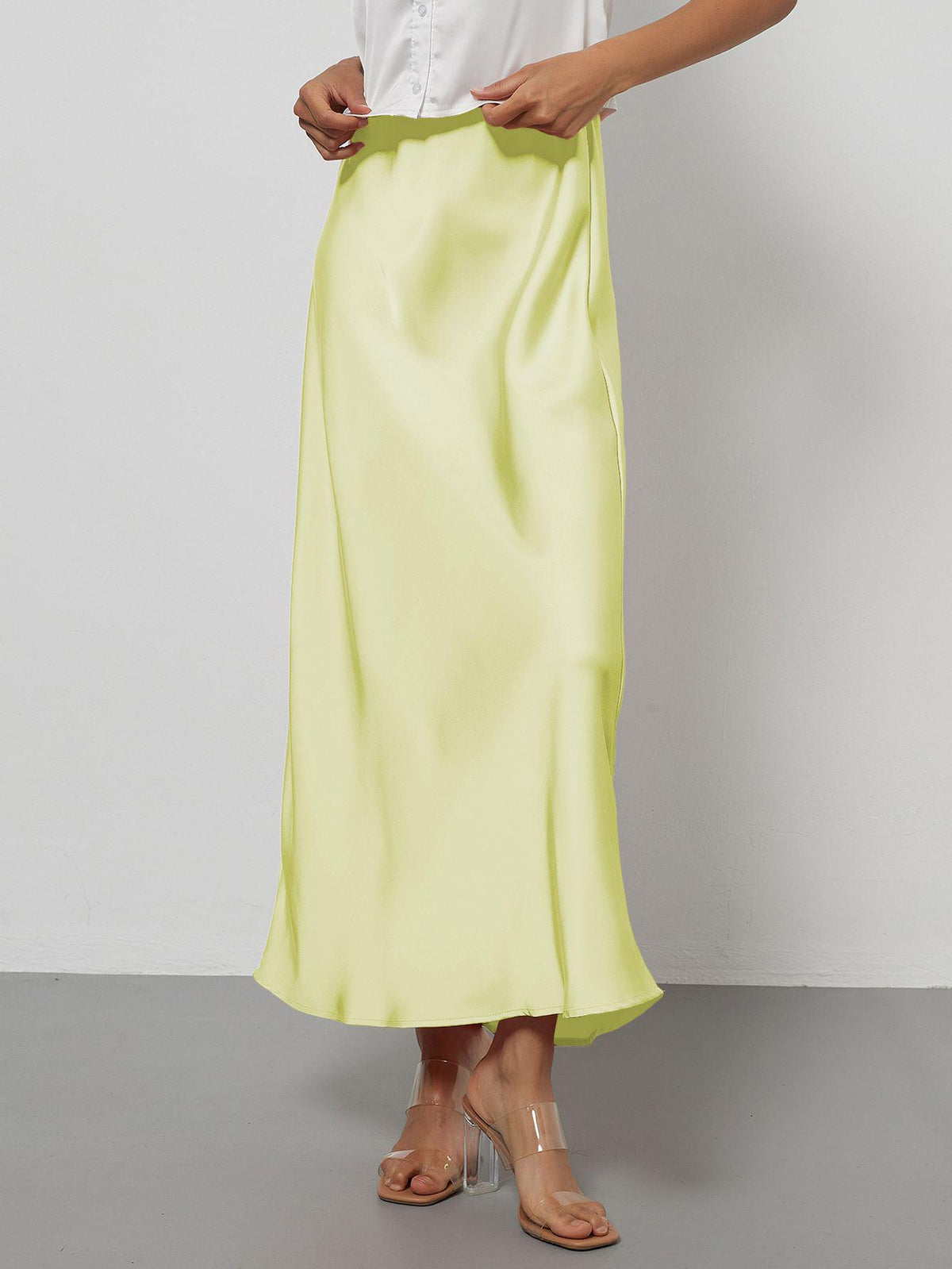 Elegant pale yellow satin midi skirt with a slim, flowy silhouette worn by a model.