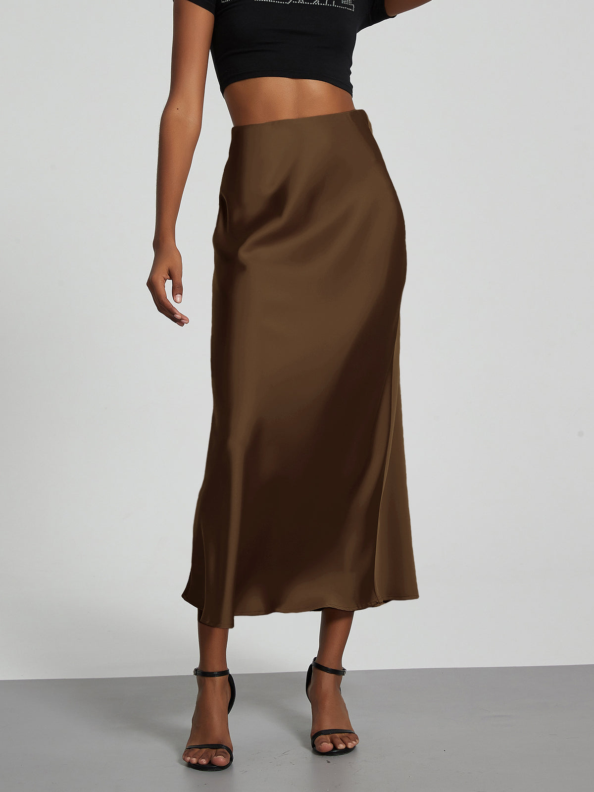 Elegant brown satin midi skirt with a slim, flowy silhouette worn by a model.