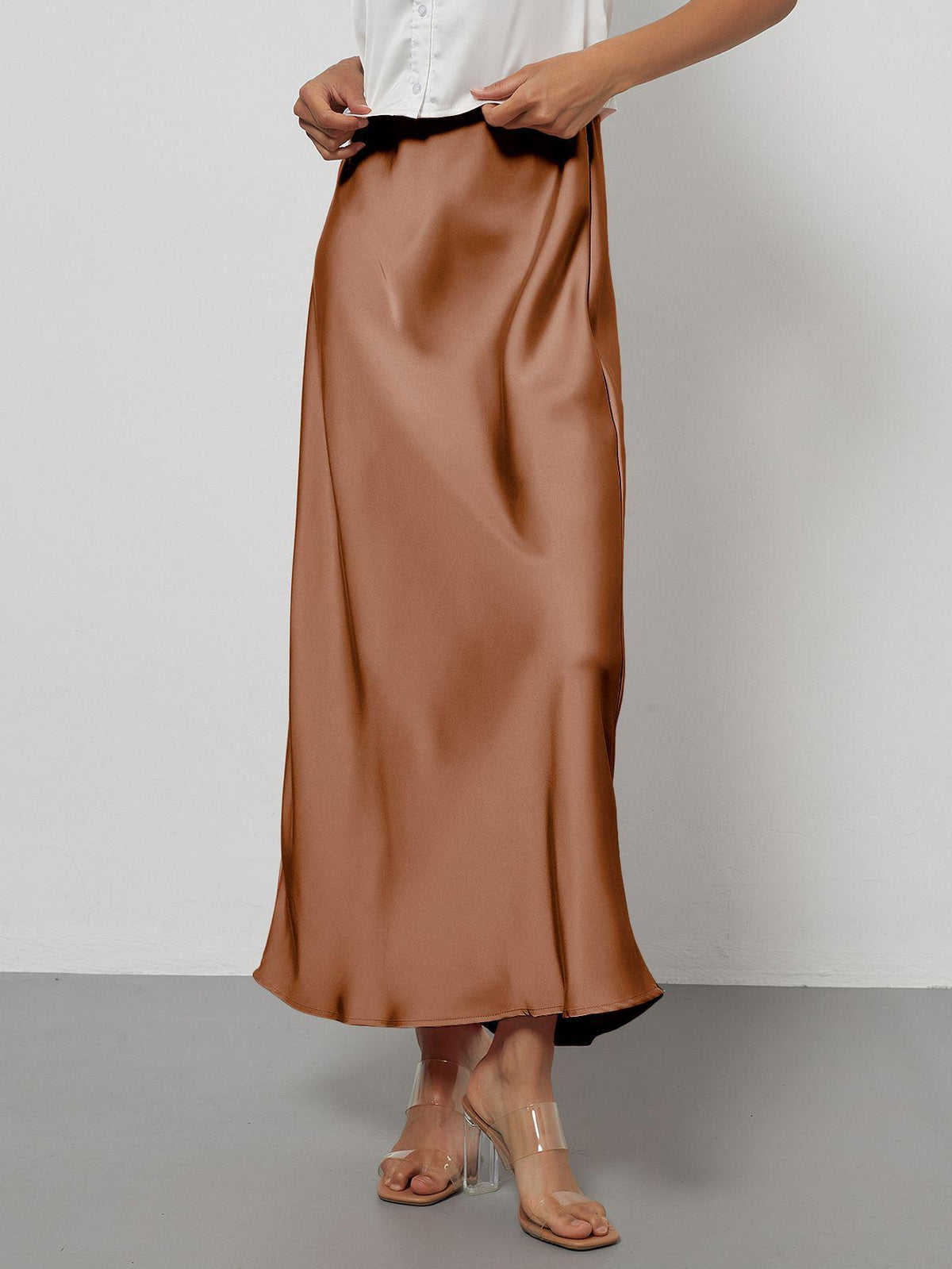 Elegant brown satin midi skirt with a slim, flowy silhouette worn by a model.