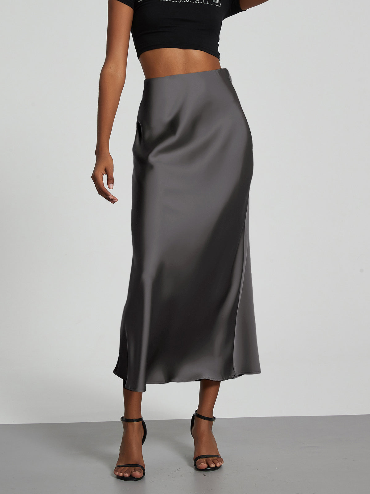 Elegant grey satin midi skirt with a slim flowy fit worn by a model.
