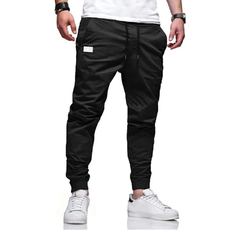 Man wearing Mandotos International black jogger cargo harem sweatpants and white sneakers.