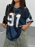 Woman wearing a navy blue oversized jersey with white number 91 and gold cross necklace.