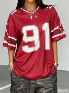 Woman wearing a red Mandotos International oversized jersey with white number 91 print and camo pants.