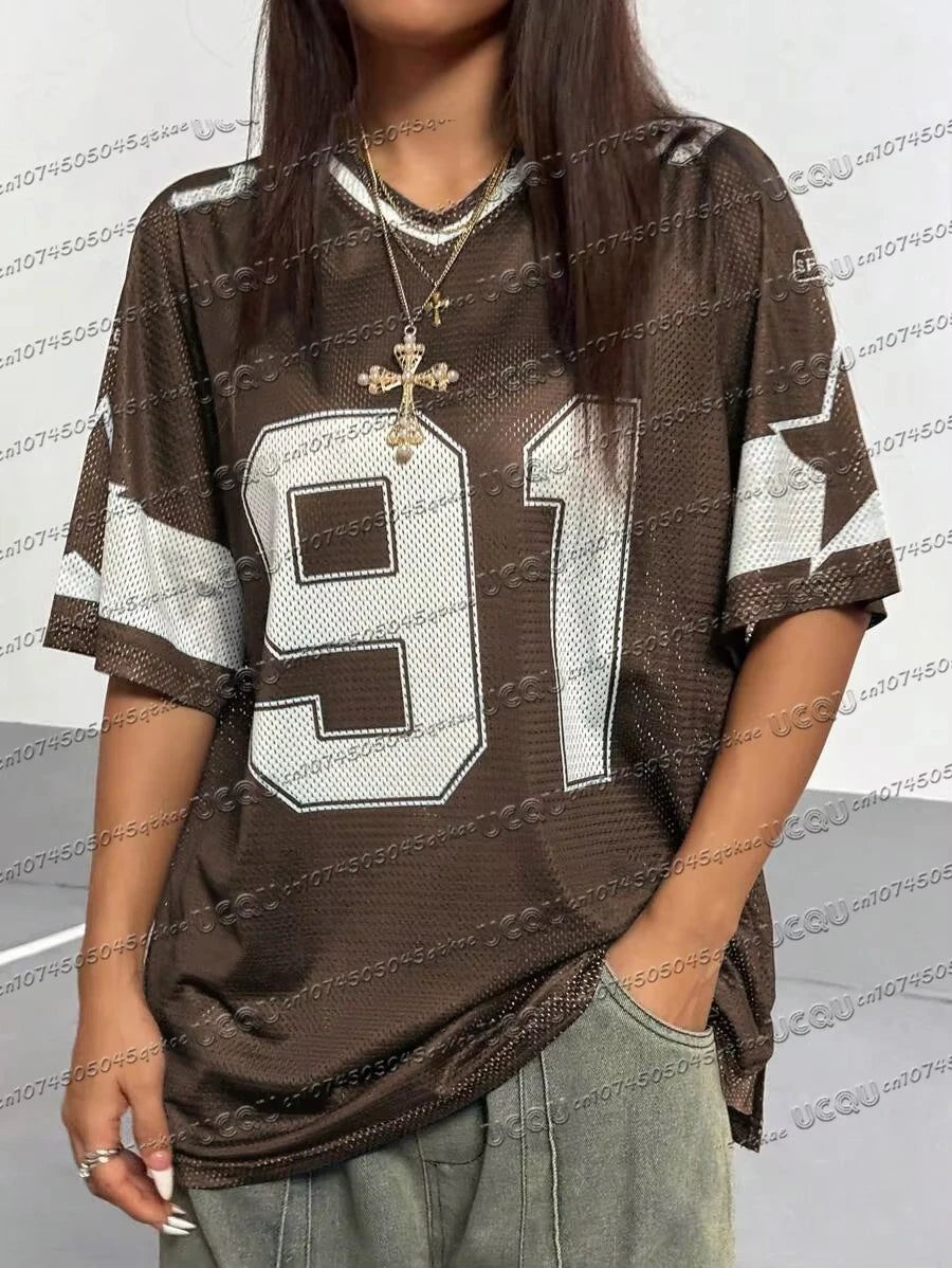 Woman wearing a loose brown summer t-shirt with a white 91 digital print and gold cross necklaces.