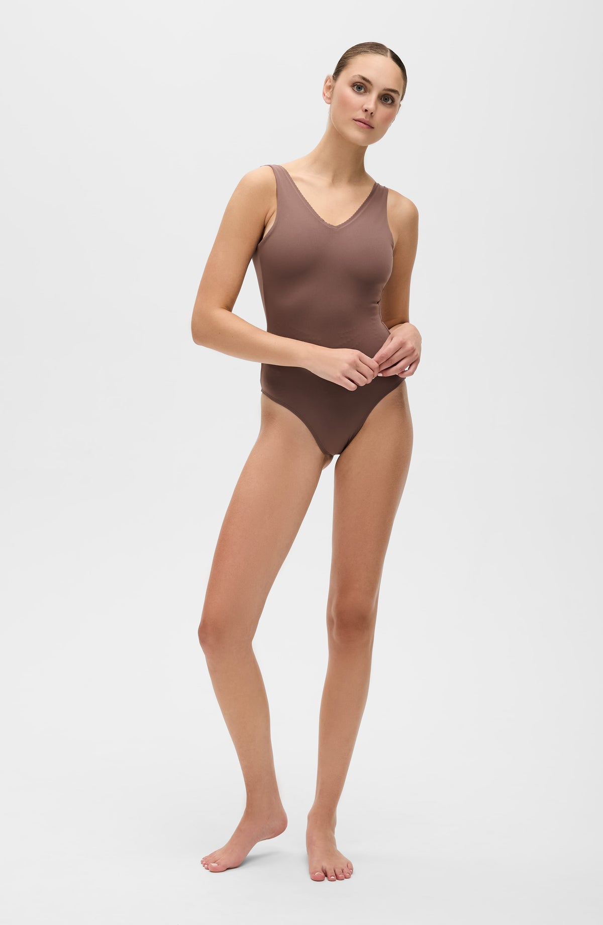Woman modeling brown one-piece swimsuit with V-neck, sleek design, perfect for beach or pool