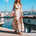 Woman wearing a Mandotos International elegant deep V floral print dress by a harbor with boats.