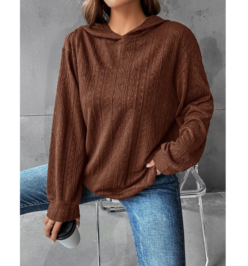 A woman wearing a brown textured casual long sleeve hoodie and blue jeans.