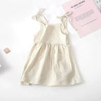 Toddler girl wearing a white cotton sundress with pink floral patterns, sleeveless and lightweight, by MANDOTOS.