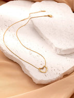 Stainless steel twist hollow heart necklace on a clavicle chain, featuring a delicate, modern design by MANDOTOS.