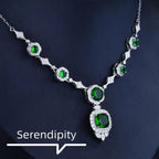 Mandotos Emerald Elegance white gold necklace with a central emerald gemstone and intricate gold detailing.