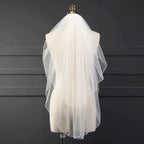 Ethereal double-tiered veil by MANDOTOS featuring delicate lace and soft tulle layers for a graceful bridal look.