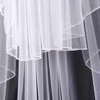 Ethereal double-tiered veil by MANDOTOS featuring delicate lace and flowing tulle for a romantic bridal look.