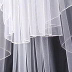 Ethereal double-tiered veil by MANDOTOS featuring delicate lace and sheer fabric, perfect for bridal or special occasion wear.